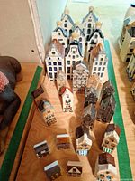 Front view showing rows of metal and ceramic miniature canal houses on wooden surface