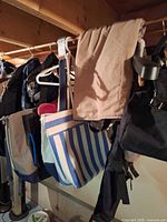 Multiple backpacks and totes hanging on rail