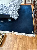 Overall view showing navy wool rug with white fringe under furniture
