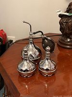 Three chrome atomizers on table showing overall appearance