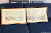 Both framed lithographs side-by-side on sofa