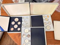 Three open RCM proof sets showing coins and empty capsule wells