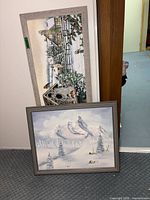 Two framed winter canvas prints leaning against wall