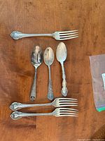 All six sterling silver flatware pieces—four forks and two spoons—laid out showing patterns and condition