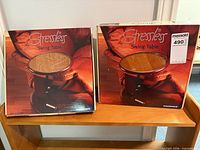 Two sealed Stressless Swing Table boxes on shelf