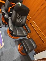 Black leather swivel recliner with matching ottoman on round wood bases