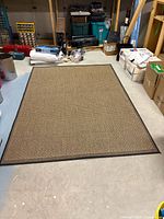 Full view of rectangular tan and black woven area rug on floor