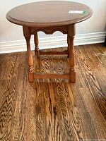 Full view of medium brown round side table with turned legs and stretcher base
