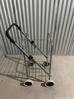Side view of folded-open cart showing frame, wheels, handle