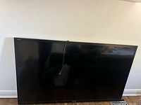 Front view of Sharp Aquos TV leaning against wall