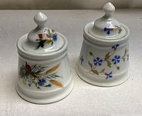 Two white floral BIA Cordon Bleu lidded jars front view