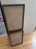 Front view of stacked Packard Bell speakers showing woven cane grilles and wood cabinets
