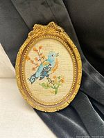 Full view of oval framed needlepoint art