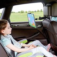 Child watching tablet mounted to car headrest
