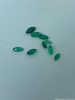 Group of 10 marquise emeralds on light background