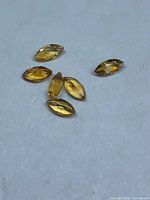 Six loose marquise-cut yellow-orange sapphires on white background