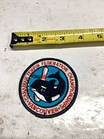 Front view of round embroidered patch with orca and bowling pin, tape measure shows approx 3 in diameter