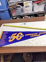Full pennant showing 50th anniversary design and measuring tape for scale