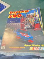 Front cover of 1987 Daytona 500 program showing drivers, trophy, race car, date and location