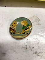 front view of enamel pin showing mascots and color details
