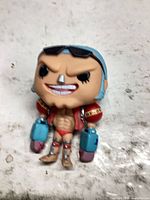 Front view of Franky vinyl figure lying on surface showing facial features, torso, and arm details