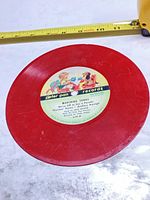 Front of red 7-inch Peter Pan flexi disc showing multicolor label and track titles