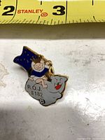 Front view of enamel lapel pin with ruler for scale
