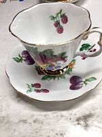 Teacup on saucer showing fruit pattern and gold trim