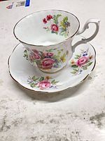 Teacup on saucer showing floral pattern and gold rim