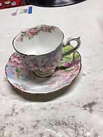 Teacup on saucer showing floral design and gold trim