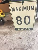 Front view of aluminum speed limit sign showing Maximum 80 km/h text and overall wear