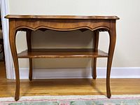 Front view showing scalloped apron, cabriole legs, lower shelf