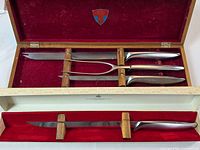 Open wooden case showing Durendal, Snickersnee knives and Ron meat fork with red lining; below, Balmung knife in Birks box