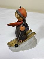 Side view of porcelain child skier on snow base