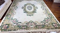 Full view of ivory wool rug showing central floral medallion and border