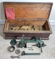 Open wooden chest showing burlap lining, instruction leaflet, cast-iron parts arranged in front