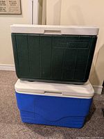 Front view of stacked green Coleman and blue unbranded coolers