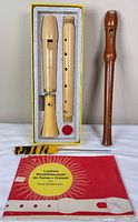 Both recorders, cleaning rod, music book, boxed recorder shown together