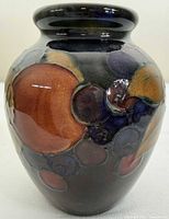 Front view of Moorcroft Pomegranate vase showing fruit motifs on dark blue ground