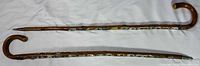 Full view of both walking sticks showing handles, enamel badges and ferrules