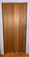 Full view of closed accordion wood door in frame