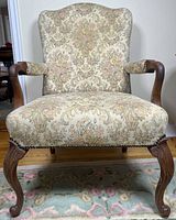 Front view of the armchair showing upholstery, carved cabriole legs, nailhead trim