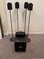 Full set showing powered subwoofer, five satellite/center speakers and four stands