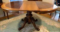 Full view of oval dining table with leaf inserted showing pedestal base