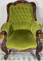 Front view showing full chair, tufted back, carved wood frame, upholstery