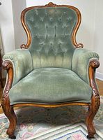 Front view of green velvet armchair showing carved wood frame and upholstery