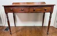 Front view of mahogany writing desk showing drawers and legs