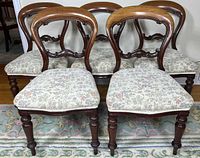 Front view of five balloon-back chairs showing carved backs, turned legs, floral seats