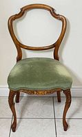Front view of carved wood side chair with green velvet seat