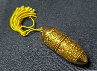 Closed bullet-shaped gold-tone needle kit with tassel